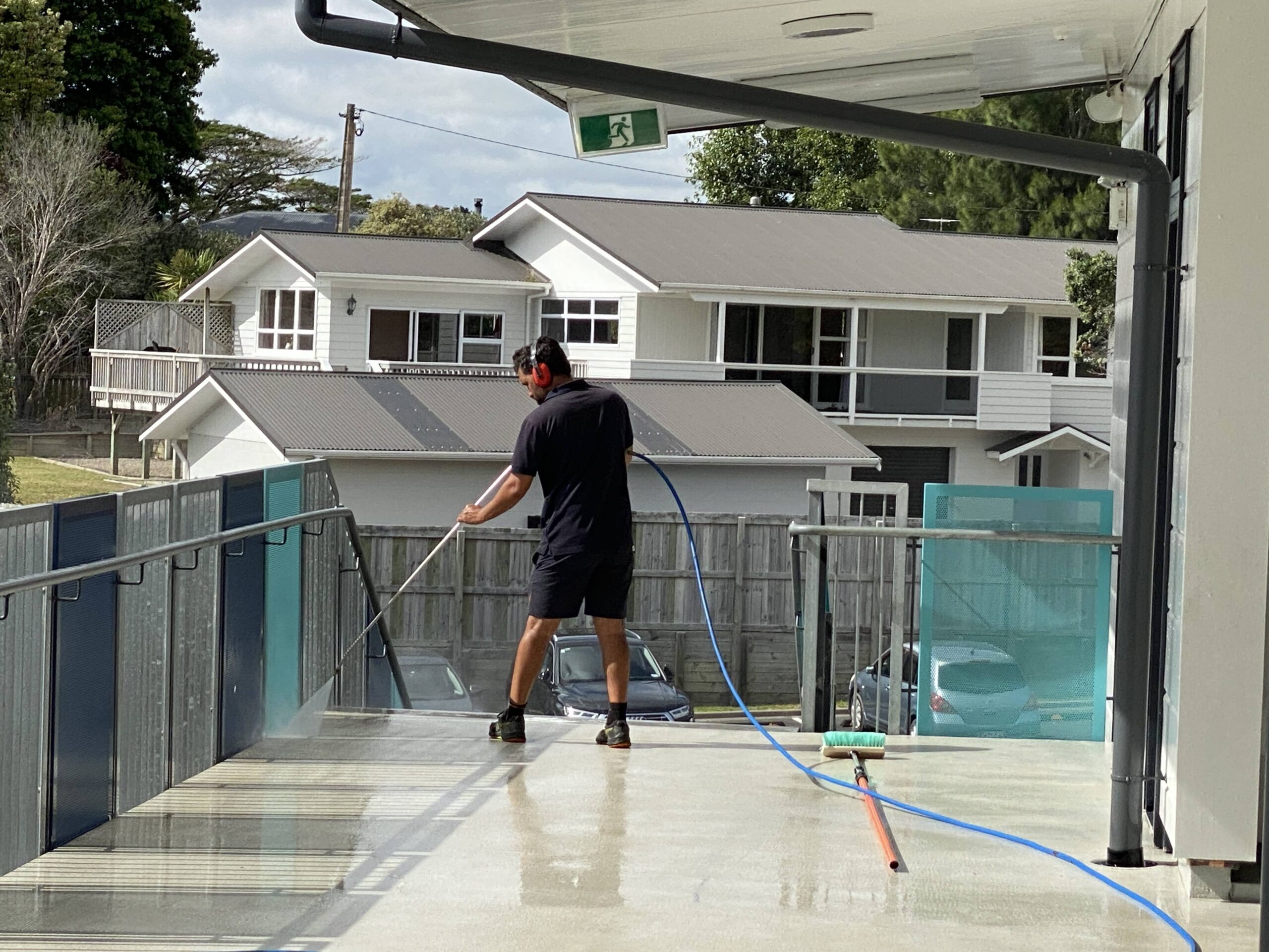 Man high pressure washing concrete horizontal surface