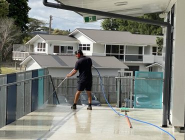 Man high pressure washing concrete horizontal surface